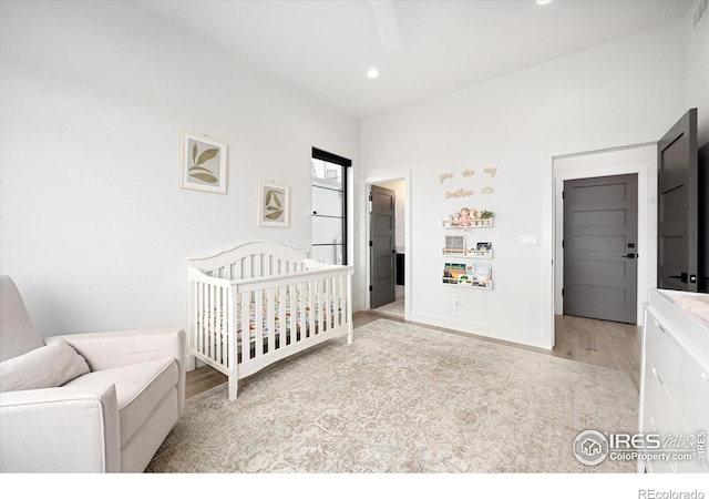 bedroom with visible vents, baseboards, recessed lighting, wood finished floors, and a nursery area