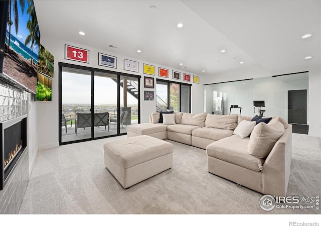 carpeted living room featuring visible vents, recessed lighting, and a warm lit fireplace