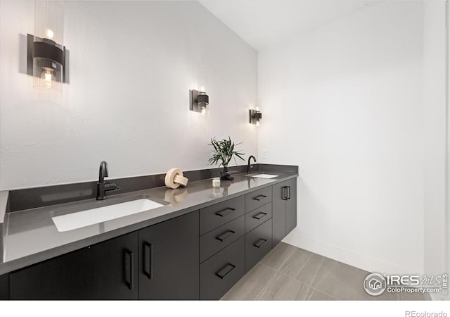 full bath featuring double vanity, baseboards, and a sink