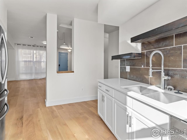 kitchen with hanging light fixtures, white cabinetry, sink, and light hardwood / wood-style floors