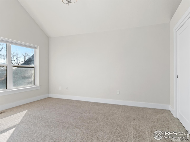 empty room featuring vaulted ceiling and light carpet