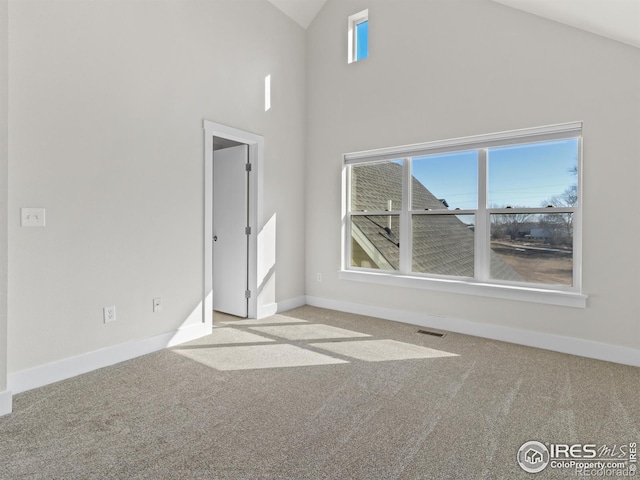 spare room with high vaulted ceiling and light carpet