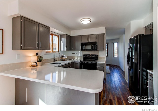 kitchen featuring sink, kitchen peninsula, dark hardwood / wood-style floors, and black appliances