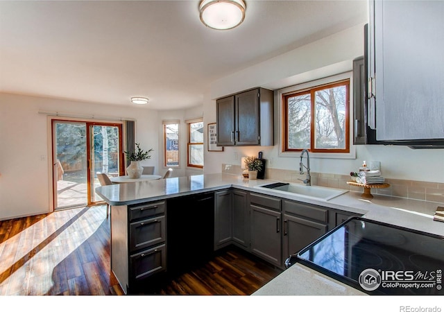 kitchen featuring sink, dark wood-type flooring, black dishwasher, range with electric stovetop, and kitchen peninsula