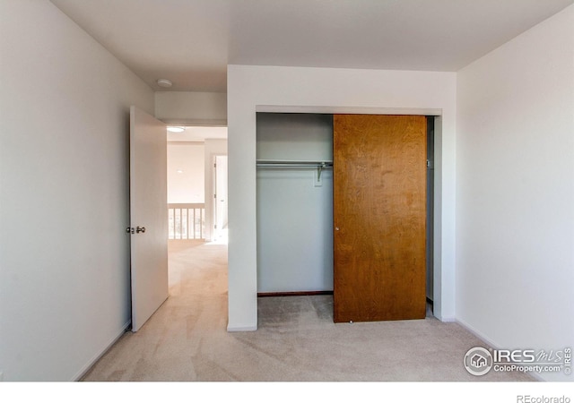 unfurnished bedroom with light carpet and a closet