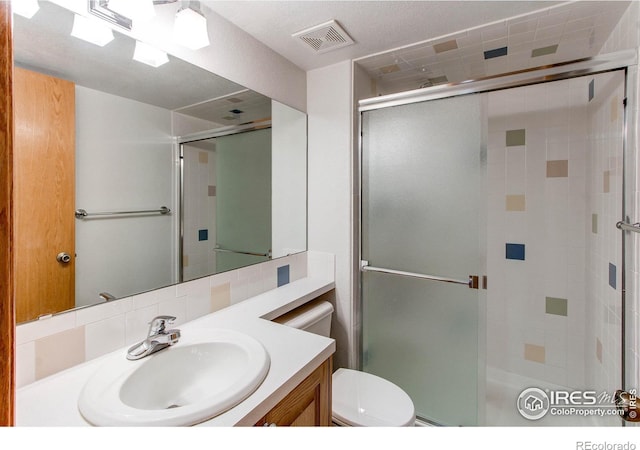 bathroom featuring vanity, toilet, and an enclosed shower