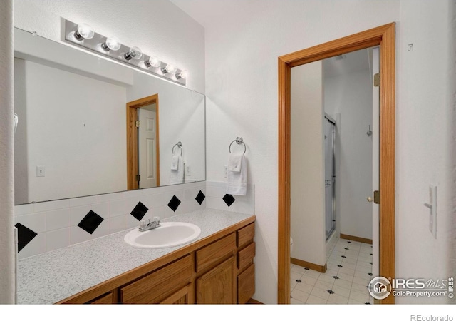 bathroom featuring vanity, decorative backsplash, and walk in shower