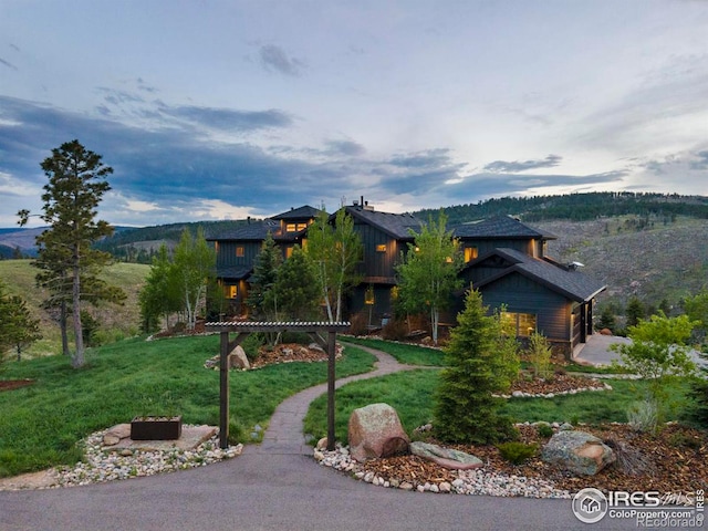 view of front of home with a mountain view and a front lawn