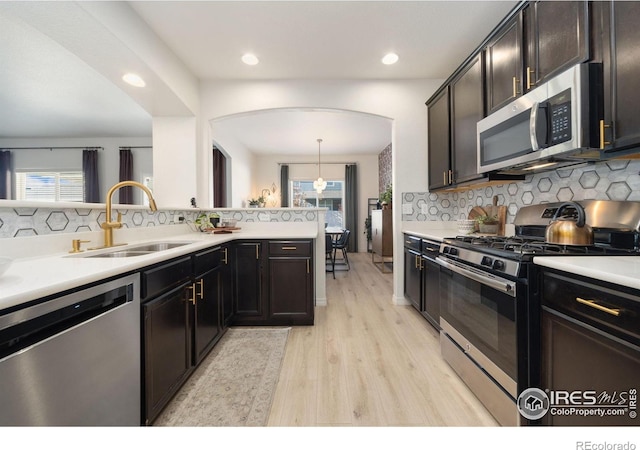 kitchen with stainless steel appliances, tasteful backsplash, a sink, and light countertops