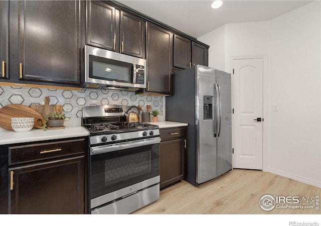 kitchen featuring dark brown cabinetry, appliances with stainless steel finishes, light countertops, light wood-type flooring, and backsplash