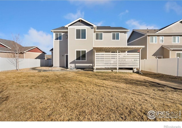 rear view of property featuring a fenced backyard and a lawn