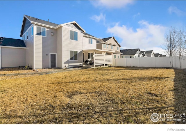 rear view of property with fence and a yard