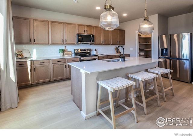 kitchen with pendant lighting, sink, a breakfast bar area, a kitchen island with sink, and stainless steel appliances