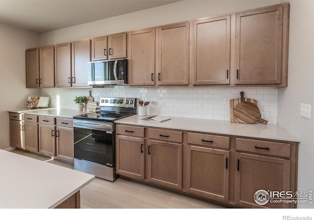 kitchen featuring stainless steel appliances, light wood-type flooring, and backsplash