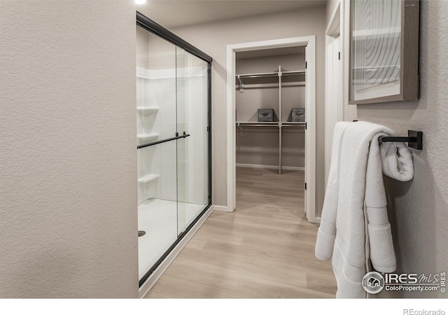 bathroom with hardwood / wood-style flooring and a shower with door