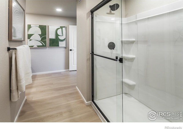 bathroom with an enclosed shower and hardwood / wood-style floors