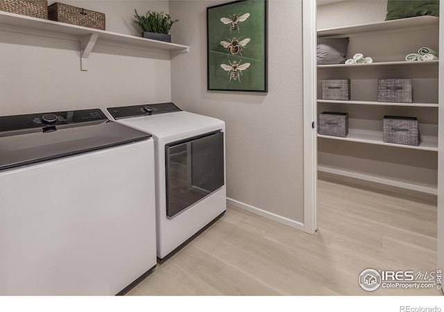 laundry area with washer and clothes dryer and light hardwood / wood-style floors