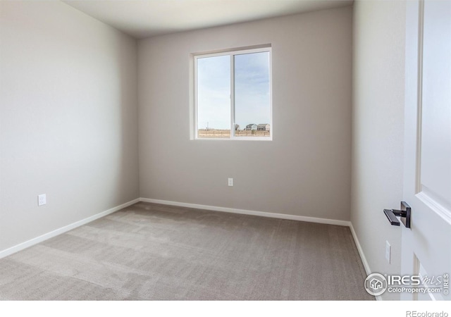 carpeted empty room featuring baseboards