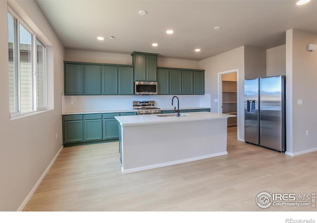 kitchen featuring appliances with stainless steel finishes, light countertops, light wood-style floors, and a sink