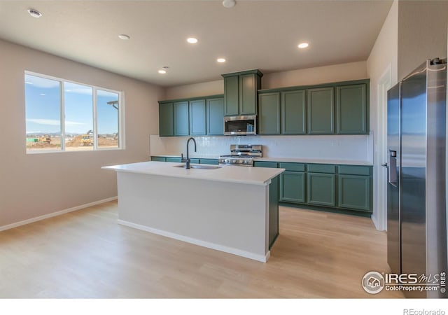 kitchen with green cabinetry, stainless steel appliances, decorative backsplash, and a sink