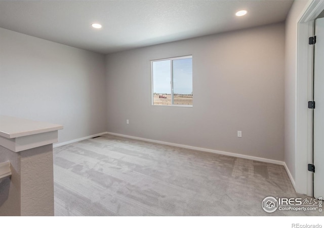 unfurnished room with recessed lighting, baseboards, and light colored carpet