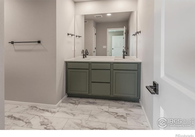 full bathroom with double vanity, marble finish floor, baseboards, and a sink