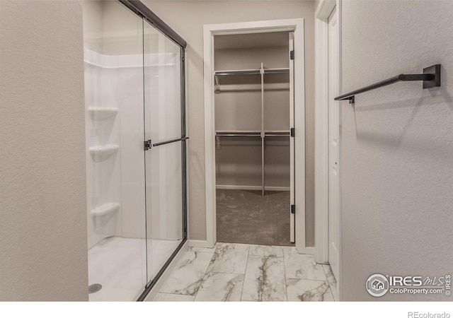 bathroom with marble finish floor, a stall shower, and a spacious closet