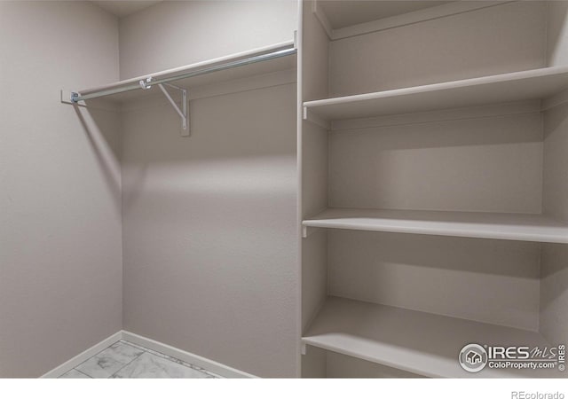 walk in closet featuring marble finish floor