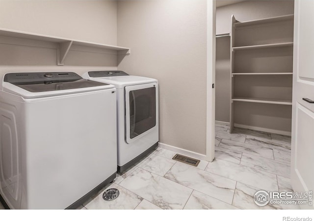 clothes washing area with visible vents, marble finish floor, washing machine and dryer, and laundry area