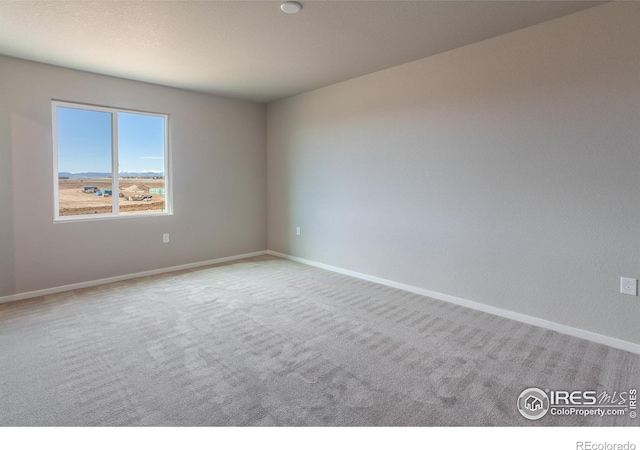 carpeted spare room featuring baseboards