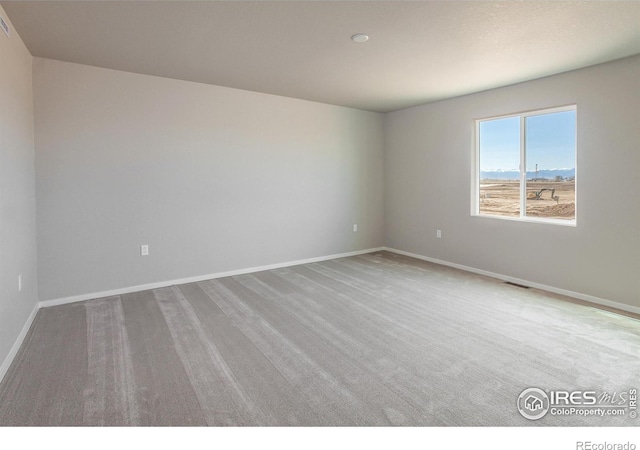 carpeted spare room with visible vents and baseboards