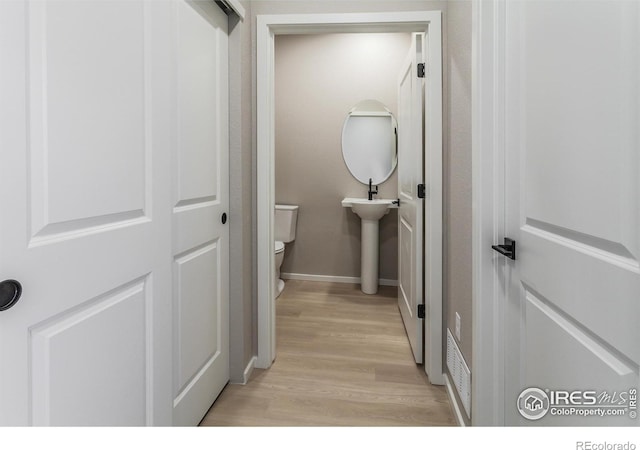 bathroom featuring toilet, baseboards, and wood finished floors