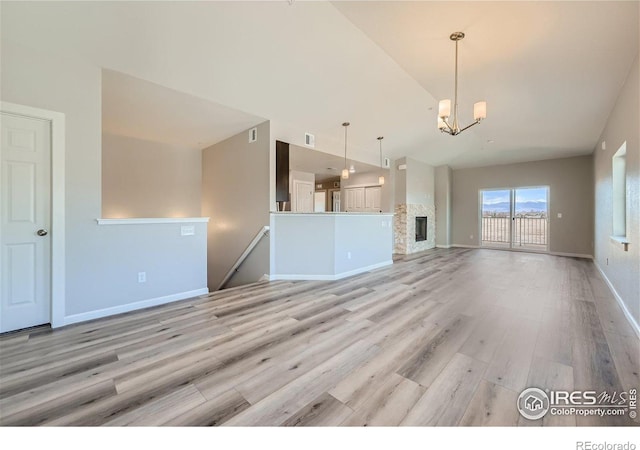 unfurnished living room with an inviting chandelier and light wood-type flooring