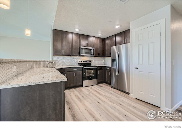 kitchen with sink, dark brown cabinets, hanging light fixtures, stainless steel appliances, and backsplash