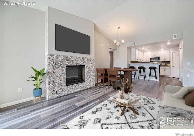 living room featuring vaulted ceiling, dark hardwood / wood-style flooring, and a chandelier