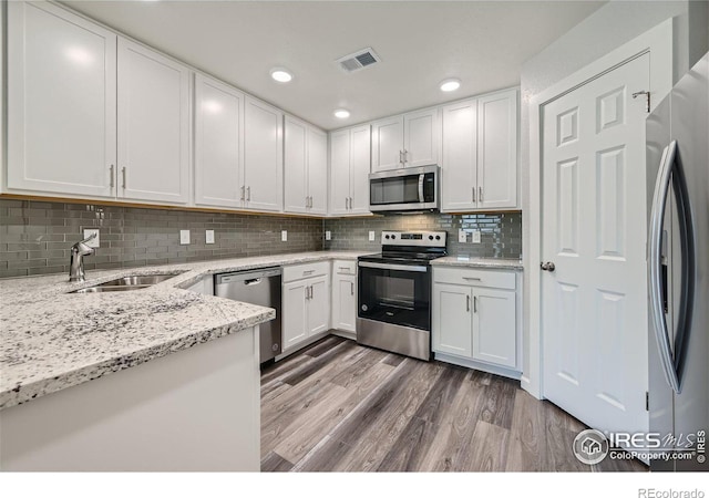 kitchen featuring white cabinetry, light stone countertops, stainless steel appliances, and sink