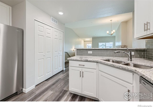 kitchen with sink, white cabinetry, decorative light fixtures, stainless steel fridge, and white dishwasher