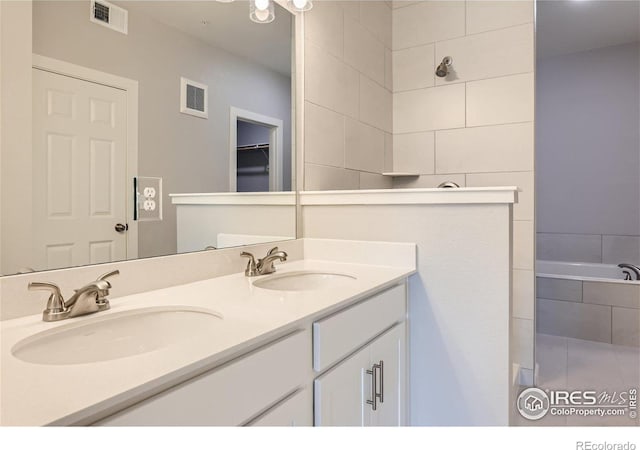 bathroom with vanity and tiled tub