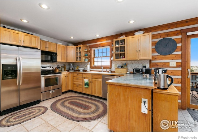 kitchen with stainless steel appliances, light brown cabinetry, kitchen peninsula, and backsplash