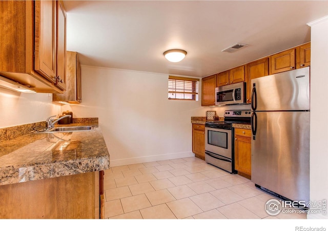 kitchen with appliances with stainless steel finishes, sink, and light tile patterned floors