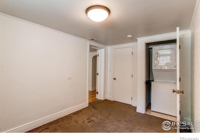 unfurnished bedroom with carpet floors, ornamental molding, and stacked washer / dryer