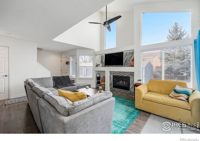 living room with wood-type flooring, a towering ceiling, and ceiling fan