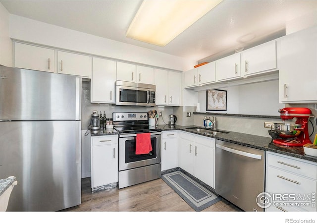 kitchen featuring white cabinetry, appliances with stainless steel finishes, sink, and dark stone counters