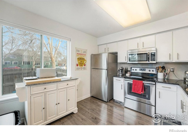 kitchen featuring white cabinetry, dark hardwood / wood-style flooring, stainless steel appliances, and dark stone countertops