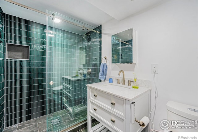 bathroom with vanity, toilet, and tiled shower