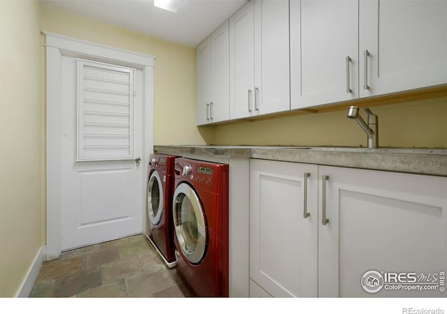 laundry room with stone finish flooring, washing machine and dryer, and cabinet space