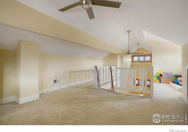 additional living space featuring a ceiling fan, light carpet, baseboards, visible vents, and vaulted ceiling