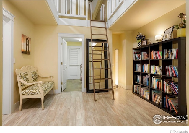 sitting room with baseboards, a high ceiling, and light wood-type flooring