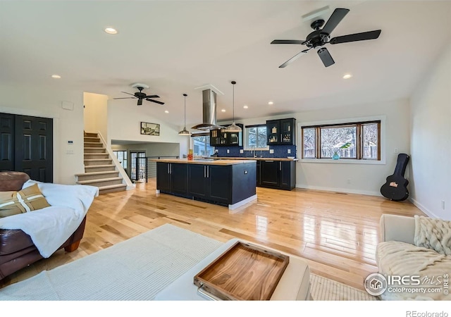 living room featuring ceiling fan, lofted ceiling, and light hardwood / wood-style flooring