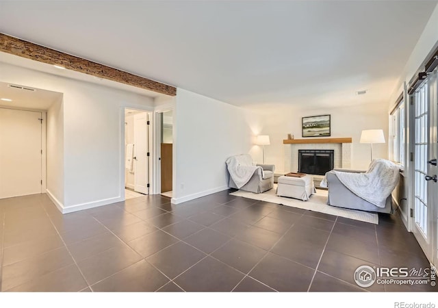 living area featuring visible vents, baseboards, dark tile patterned flooring, a fireplace, and beamed ceiling